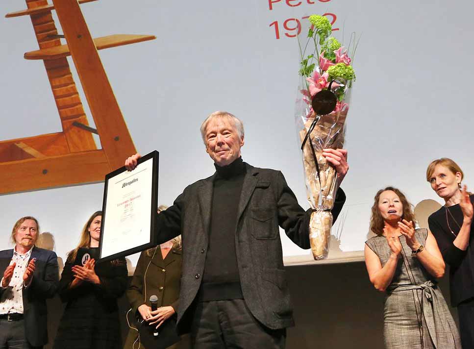 Peter Opsvik holding up award and flowers at award ceremony in 2017