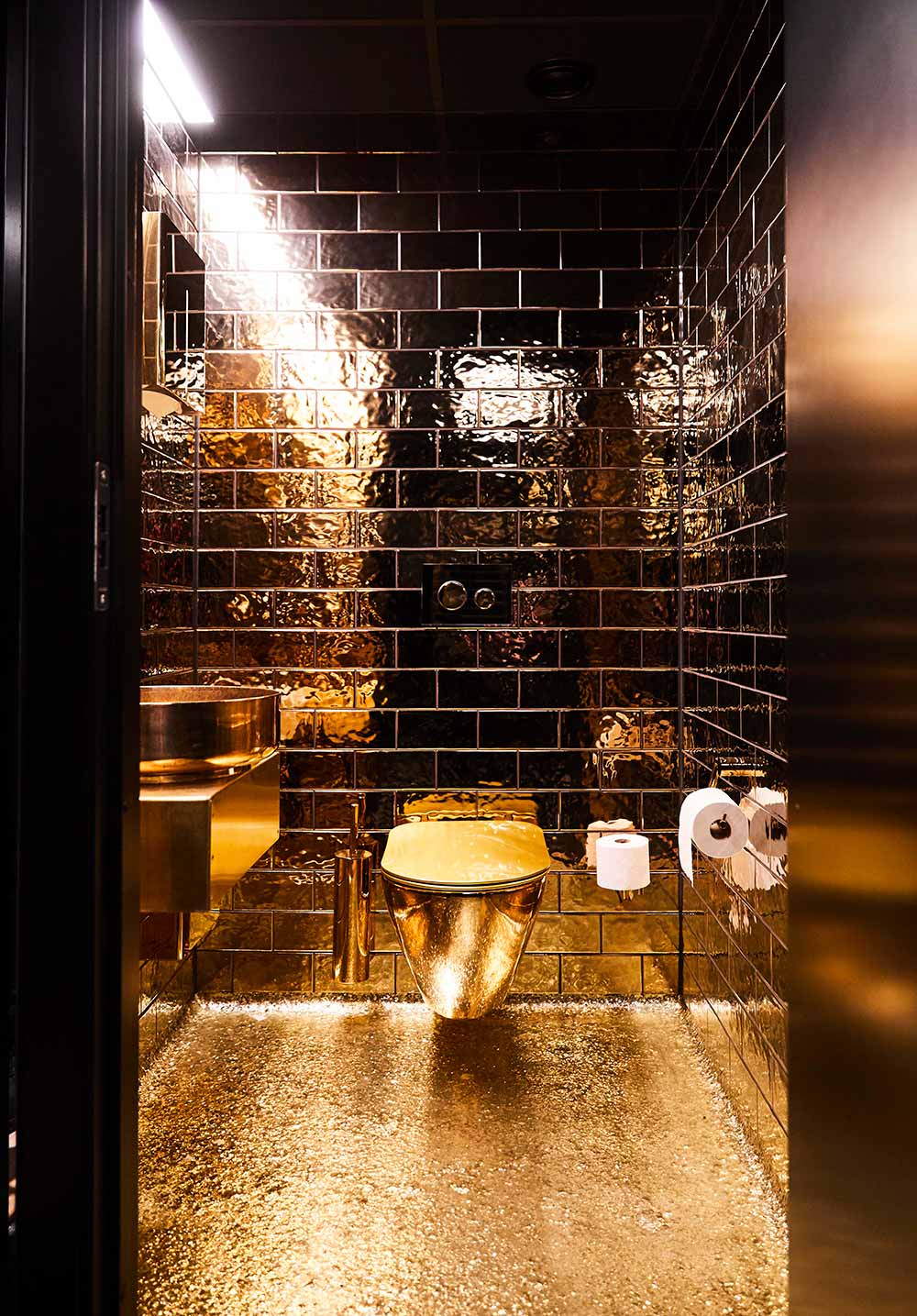 interior of golden toilet cubicle with gold floor, gold walls and gold sink, at Vipps office in Oslo