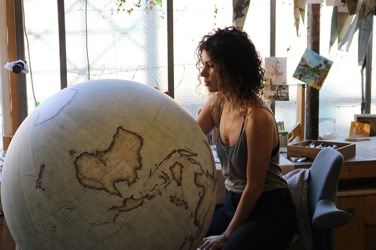 Bellerby & Co Head Painter Isis Linguanotto painting a giant globe whilst sat on a HÅG Capisco