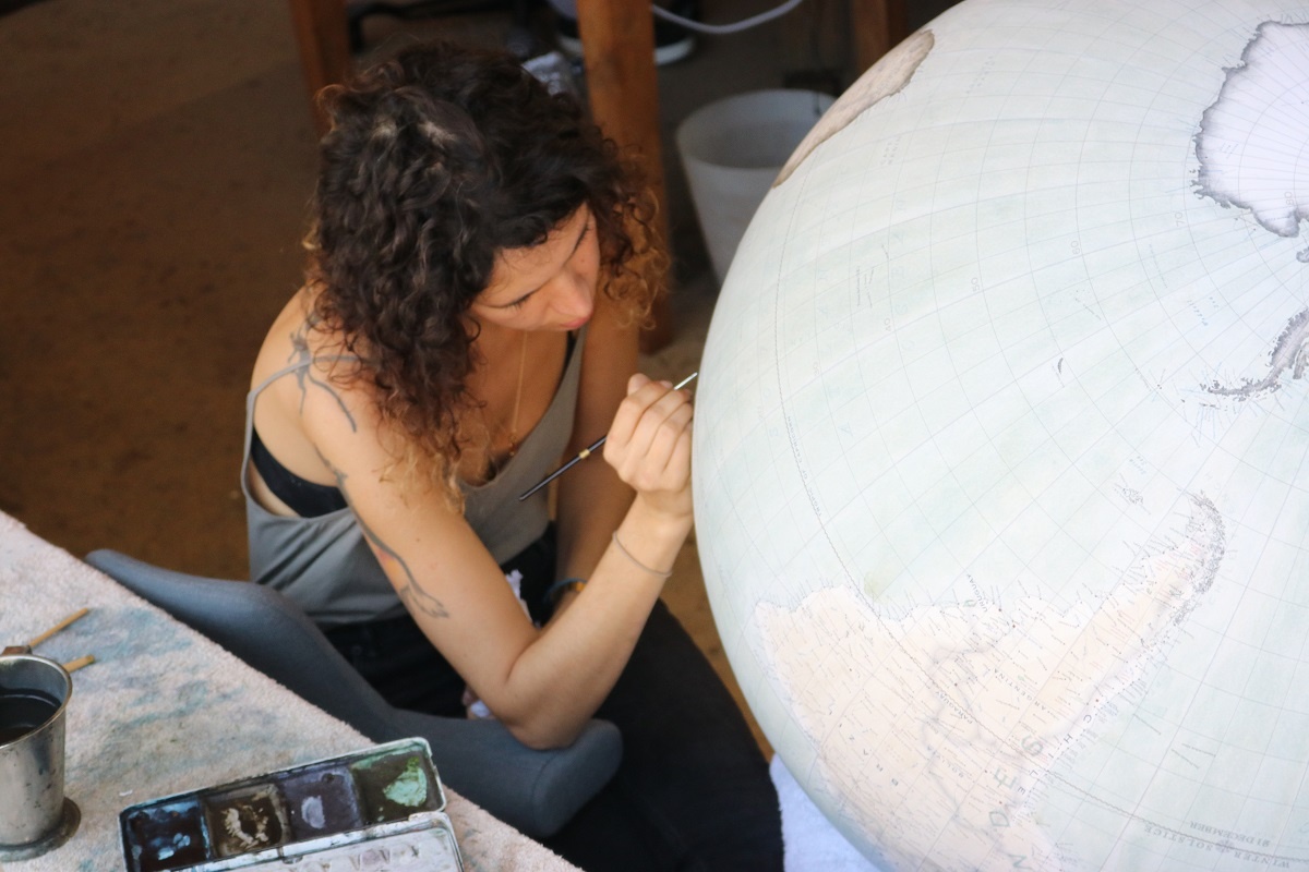 Bellerby & Co head painter Isis Linguanotto painting on a giant globe