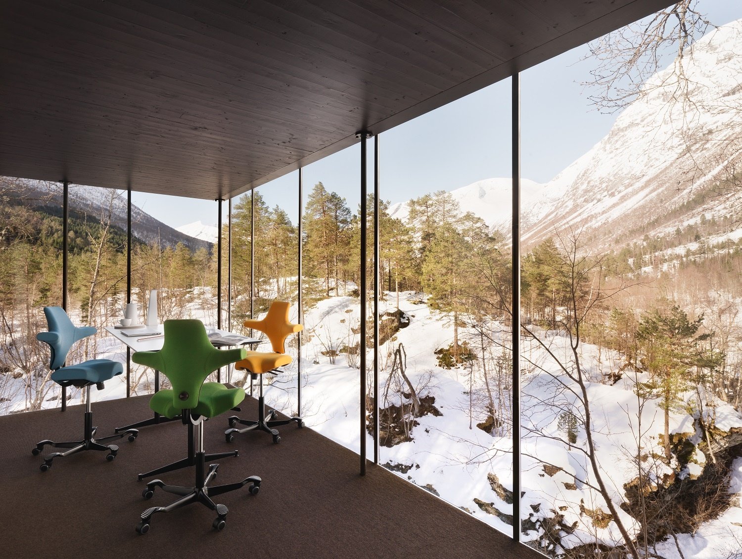 3 HÅG Capisco chairs in a glass room with snowy landscape outside